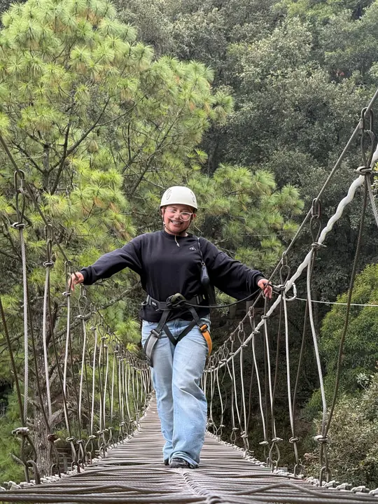 Visitante con casco y arnés cruzando el puente colgante